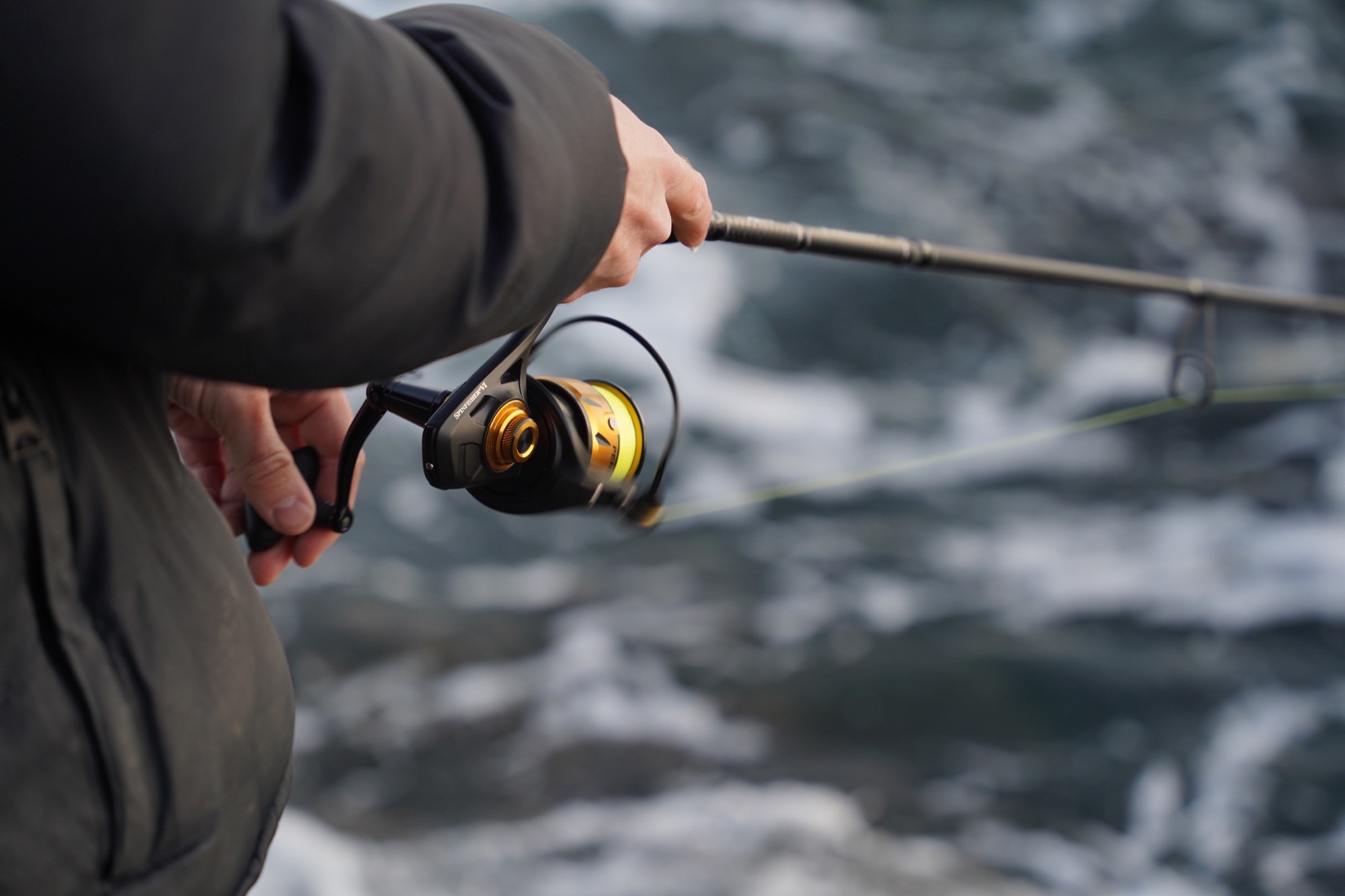 A shoreline with fishing rods on the ground and a nice sunny water